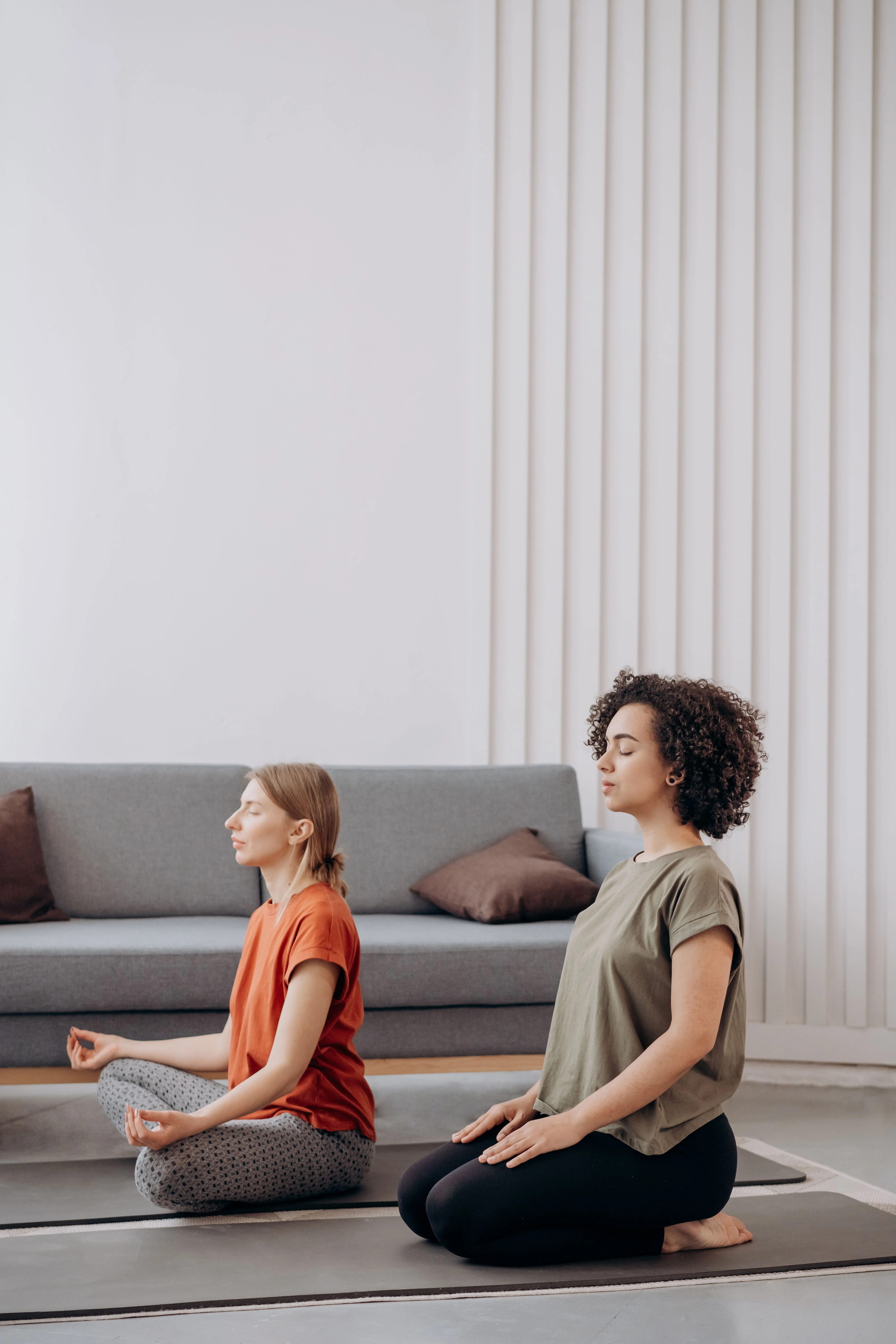 Two women sitting cross legged during a calm session at home